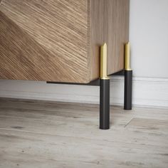 two black and gold handles on a wooden cabinet in a room with hardwood flooring