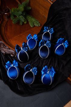 six pairs of blue velvet shoes with bows on them sitting on a black cloth covered table