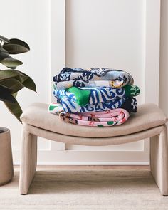 three folded towels sitting on top of a wooden bench next to a potted plant