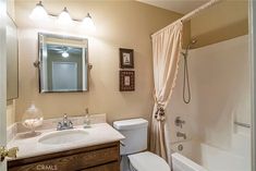 a bathroom with a sink, toilet and bathtub next to a shower curtain that is pulled down