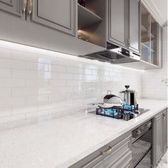 a stove top oven sitting inside of a kitchen next to gray cabinets and counter tops