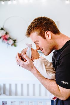 a man holding a baby in his arms and looking down at it's face