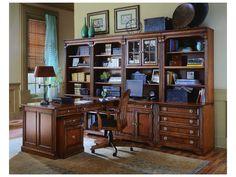 a large wooden desk sitting in front of a book shelf filled with lots of books