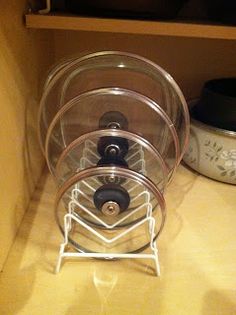 a stack of four clear containers sitting on top of a counter next to a pot