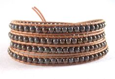 Leather wraps are a great way to add a fun, boho, chic look to any outfit.  They can be worn alone or with a bangle or another wrap for an interesting cluttered look.  The 4 mm bluish, lavender with  bronze glaze Czech glass beads, are nestled between natural Greek leather cording.  A delightful, textured, copper button finishes the look.  The bracelet is threaded twice for additional strength and durability.  It measures 32- 1/2" for a loose, comfortable fit for most size 7 - 7 1/2" wrists. This bracelet will arrive ready for gifting. I ship USPS first class.  I include delivery confirmation, when available, at no extra cost to you.  I will supply you with a tracking number.  For additional information on shipping, please see my shop policy page. I welcome all questions!  Thank you for yo Bohemian Wrap Bracelet With Black Beads For Gift, Bohemian Black Beads Wrap Bracelet Gift, Festival Hand Wrapped Wrap Bracelet, Beaded Brown Wrap Bracelet For The Beach, Beaded Brown Wrap Bracelet For Beach, Adjustable Wrap Bracelet With Black Round Beads, Adjustable Wrap Bracelet With Black Beads, Adjustable Black Beads Wrap Bracelet, Brown Beaded Wrap Bracelet For Beach