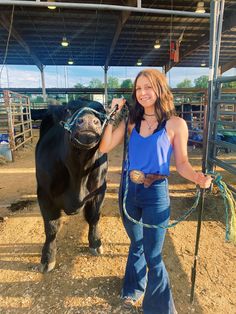 a woman standing next to a black cow