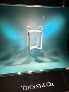 a glass display case with a white bow on it's top and tiffany & co logo below