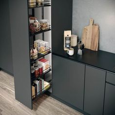 an organized pantry in the corner of a kitchen with black cabinets and gray walls, along with wooden flooring