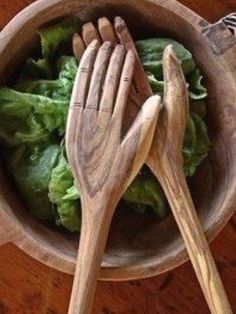 two wooden utensils in a bowl with lettuce