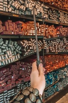 a person holding a metal object in front of a wall full of different colored boxes