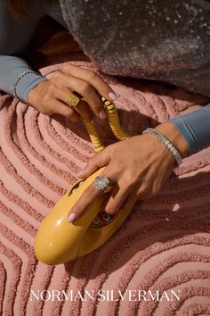 a woman holding onto a yellow computer mouse on top of a pink blanket with rings