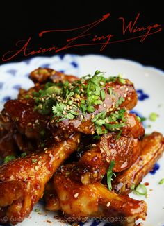 a close up of a plate of food with chicken wings on it and garnished with herbs