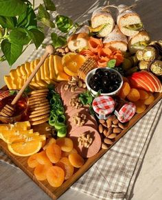 a platter filled with cheese, crackers, fruit and other snacks on a table