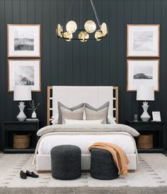 a bedroom with black and white walls, pictures on the wall, two foot stools