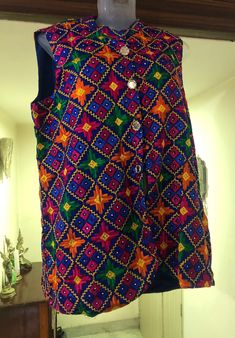 This is a beautiful Indian colorful sleeveless jacket. It is primarily a blue base with beautiful phulkari embroidery threadwork in blue, pink, green, orange and yellow with small silver diamantes throughout the piece.    This is made from a fine quality phulkari embroidery (machine embroidery) fabric in chinnon with multicolored viscose silk threadwork from Punjab. Phulkari is a very intricate embroidery technique of the State of Punjab in India. The word phul means flower and kari means craft, Sleeveless Nehru Jacket With Resham Embroidery, Embroidered Sleeveless Nehru Jacket For Festive Occasions, Traditional Sleeveless Blue Kurta, Traditional Sleeveless Kurta With Mirror Work, Multicolor Sleeveless Kurta For Festive Occasions, Festive Multicolor Sleeveless Kurta, Festive Cotton Sleeveless Nehru Jacket, Cotton Sleeveless Nehru Jacket For Festive Occasions, Festive Sleeveless Cotton Nehru Jacket