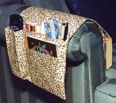 an animal print purse is hanging on the back of a green couch with books and magazines in it