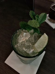 a glass filled with ice and lime on top of a table