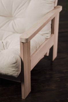 a close up of a wooden chair with white cushions