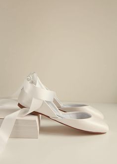 a pair of white shoes sitting on top of a book with a ribbon around it