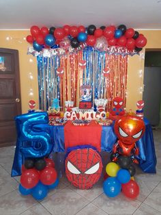 a spiderman themed birthday party with balloons and streamers on the ceiling, table