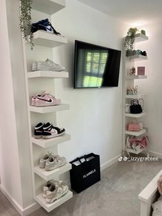 a tv mounted on the wall next to shelves filled with shoes and handbags