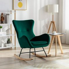 a green rocking chair next to a table with a white lamp on it in a living room