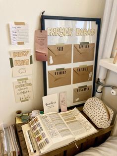 an open book sitting on top of a wooden table next to a window with papers