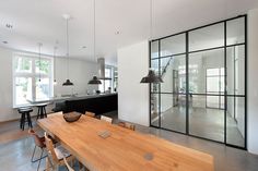 an open concept kitchen and dining room with wood table in foreground, large glass doors to the outside