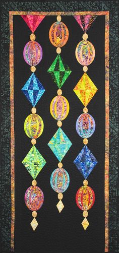 a quilted wall hanging with many different colored circles and medallions on black fabric