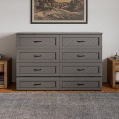 a gray dresser sitting on top of a wooden floor next to a framed painting above it