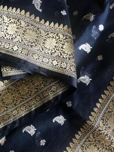 This is very lovely handloom premium banarasi silk cotton saree in black body with silver resham motifs in body and gold colour floral motifs in borders. Saree has beautiful silver zari pallu with floral motifs on either end in gold colour. Saree comes with an unstitched blouse piece. Wear it for a formal occasion or a party and you are sure to make heads turn in awe! Colour may vary depending upon lighting and individual device settings  Dry clean only All sales are final. Handloom products may Black Chanderi Saree With Zari Weaving, Black Handloom Saree For Wedding, Bollywood Style Black Cotton Silk Traditional Wear, Black Banarasi Silk Saree With Pallu, Festivals Black Banarasi Silk Saree, Black Banarasi Silk Saree For Festivals, Black Handloom Banarasi Silk Traditional Wear, Black Banarasi Silk Traditional Wear With Handloom Detail, Black Banarasi Silk Traditional Wear Handloom