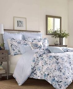 a bed with blue and white comforters in a room next to a dresser, mirror and window