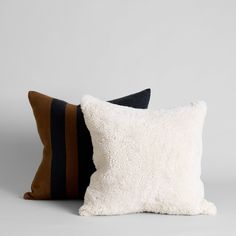 two pillows with black and brown stripes on them, one is made out of sheepskin