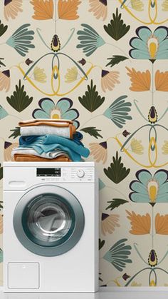 a white washer sitting next to a wall with colorful flowers on the wallpaper