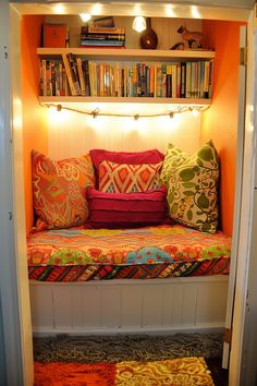 a window seat with bookshelves and pillows on it