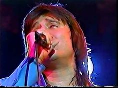 a man with long hair singing into a microphone