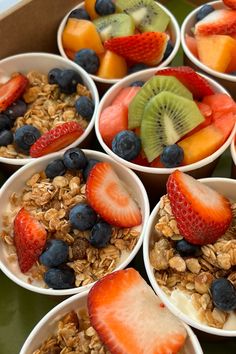 several bowls filled with fruit and granola on top of a green tray next to another bowl