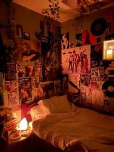 an unmade bed in a room with posters on the wall and a lit candle