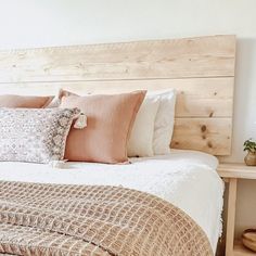 a bed with pillows and blankets on top of it next to a wooden headboard