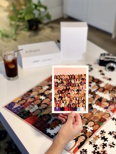 a person holding up a card with people on it in front of a table full of puzzles