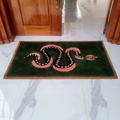 a door mat with a snake on it in the middle of a room next to wooden doors