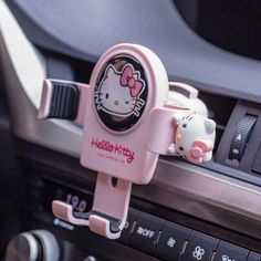 a hello kitty phone holder is attached to the dashboard of a car