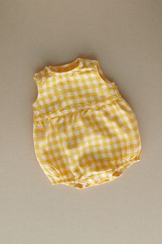 Product photos - yellow gingham. All-day comfort is guaranteed with this sleeveless romper crafted from gingham linen. The fabric is soft, breathable, and light on the skin. For simple changing, the romper is designed with popper snap fastenings on the shoulders and bottom. The waist seam in the middle adds a nice final touch to an adorable silhouette, and elasticated leg cuffs secure the romper in place. This baby romper is designed to be comfortably loose-fitting and allow for growth as the baby grows. Yellow Cotton Bubble Romper For Summer, Summer Yellow Cotton Bubble Romper, Yellow Cotton Summer Bubble Romper, Yellow Cotton Bubble Romper For Spring, Spring Yellow Cotton Bubble Romper, Sleeveless Yellow Cotton Bubble Romper, Cute Summer Plaid Bubble Romper, Casual Yellow Bubble Romper For Summer, Plaid Cotton Bubble Romper For Summer