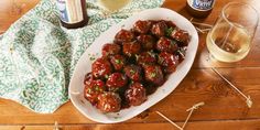 a white plate topped with meatballs next to two bottles of beer