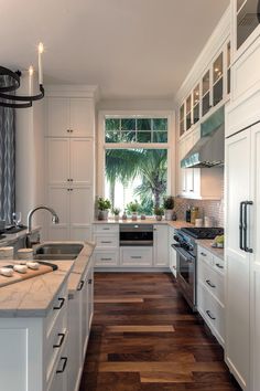 a kitchen with white cabinets and wood floors