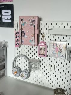 there is a white pegboard with pictures and headphones on it