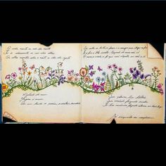 an open book with flowers and writing on the pages, in front of a black background