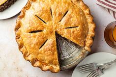 a pie with a slice missing from it on a table next to plates and utensils