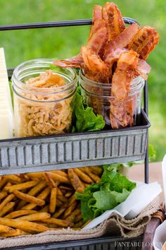 some food is sitting in a metal container on a table with other foods and cheeses