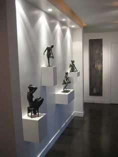 several sculptures are displayed on white pedestals in a room with dark wood flooring